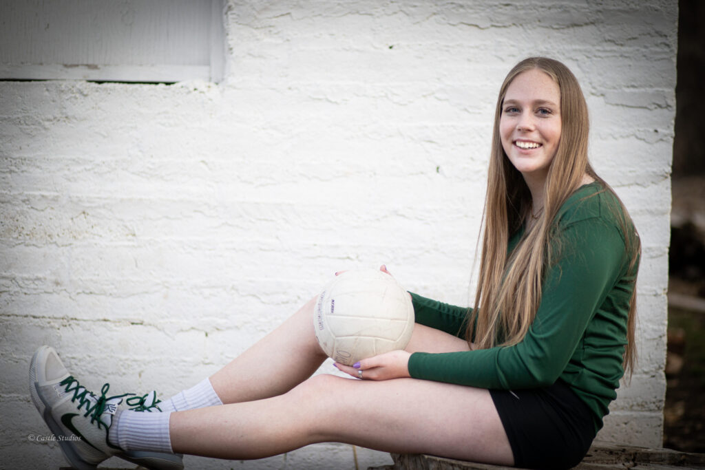 A girl is sitting on the floor holding a football in her hands.